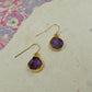 Round purple amethyst earrings on hooks finished in gold.