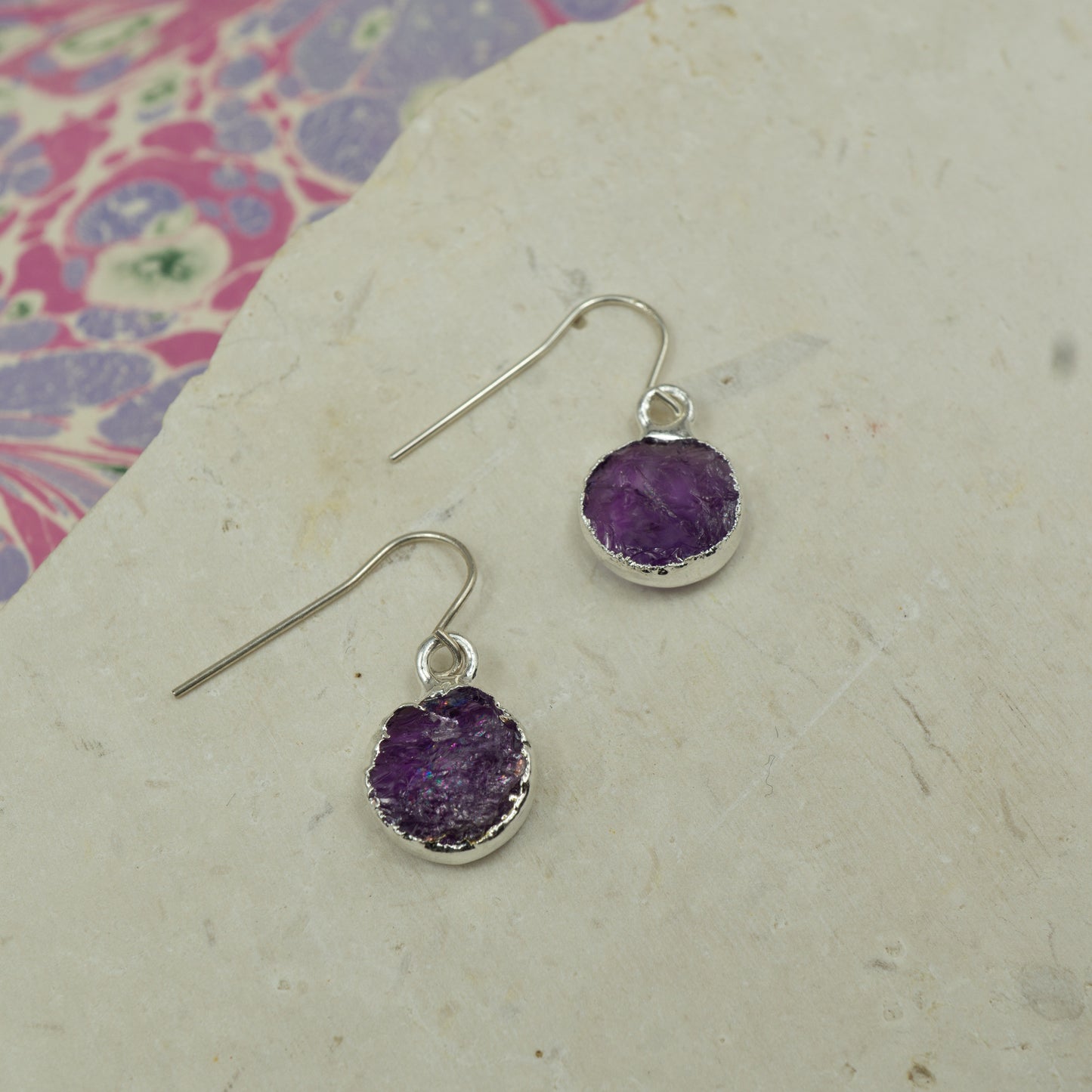 Round purple amethyst earrings on hooks finished in silver.