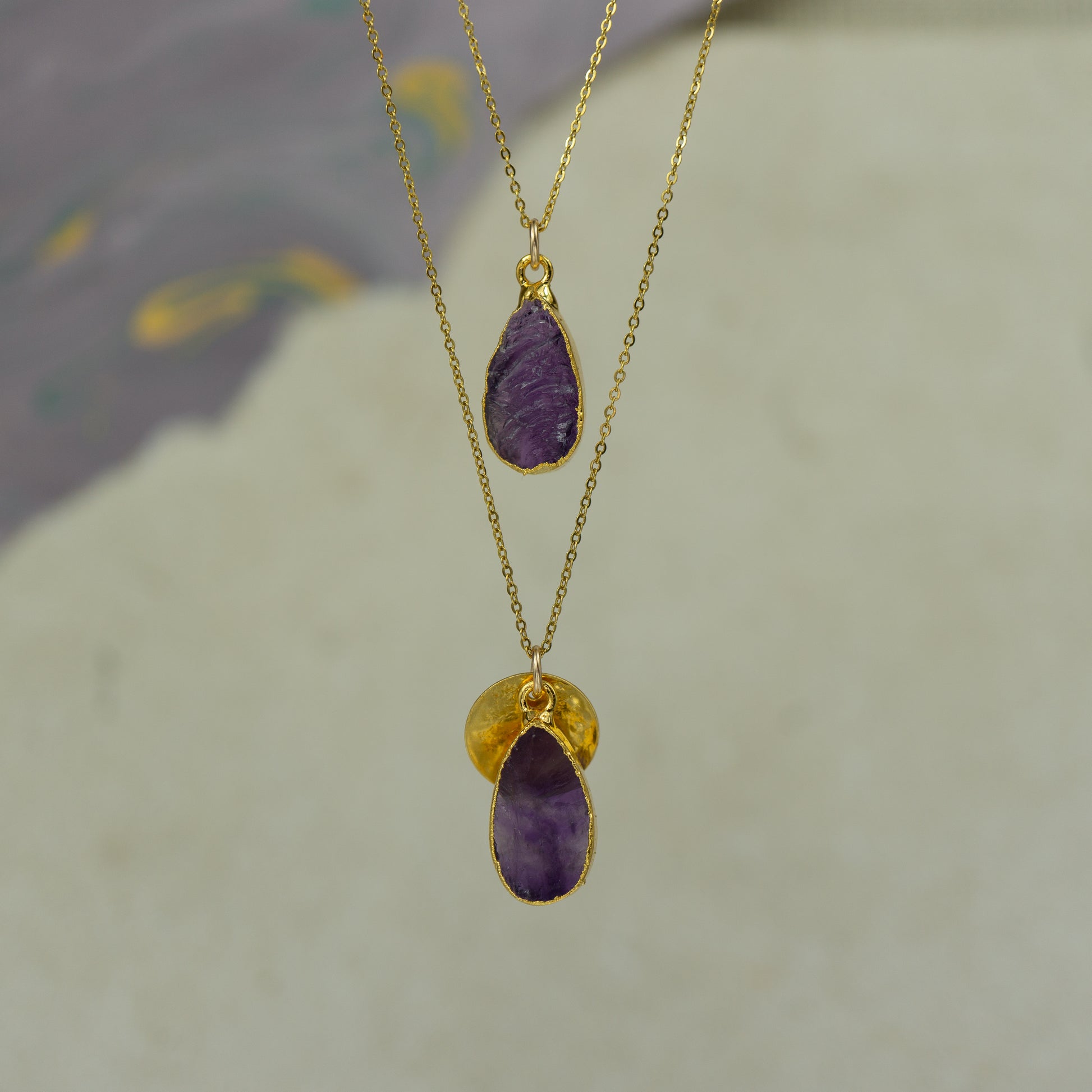 Raw purple amethyst teardrop pear shaped pendants finished in gold on a chains.