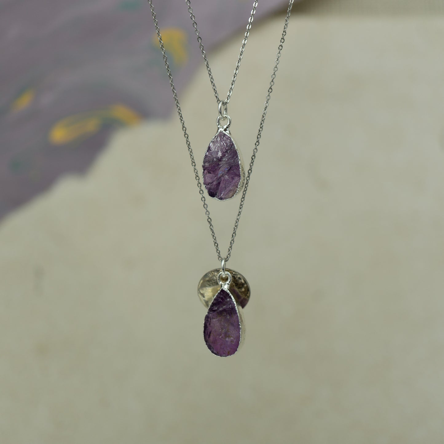Raw purple amethyst teardrop pear shaped pendants finished in silver on a chains.