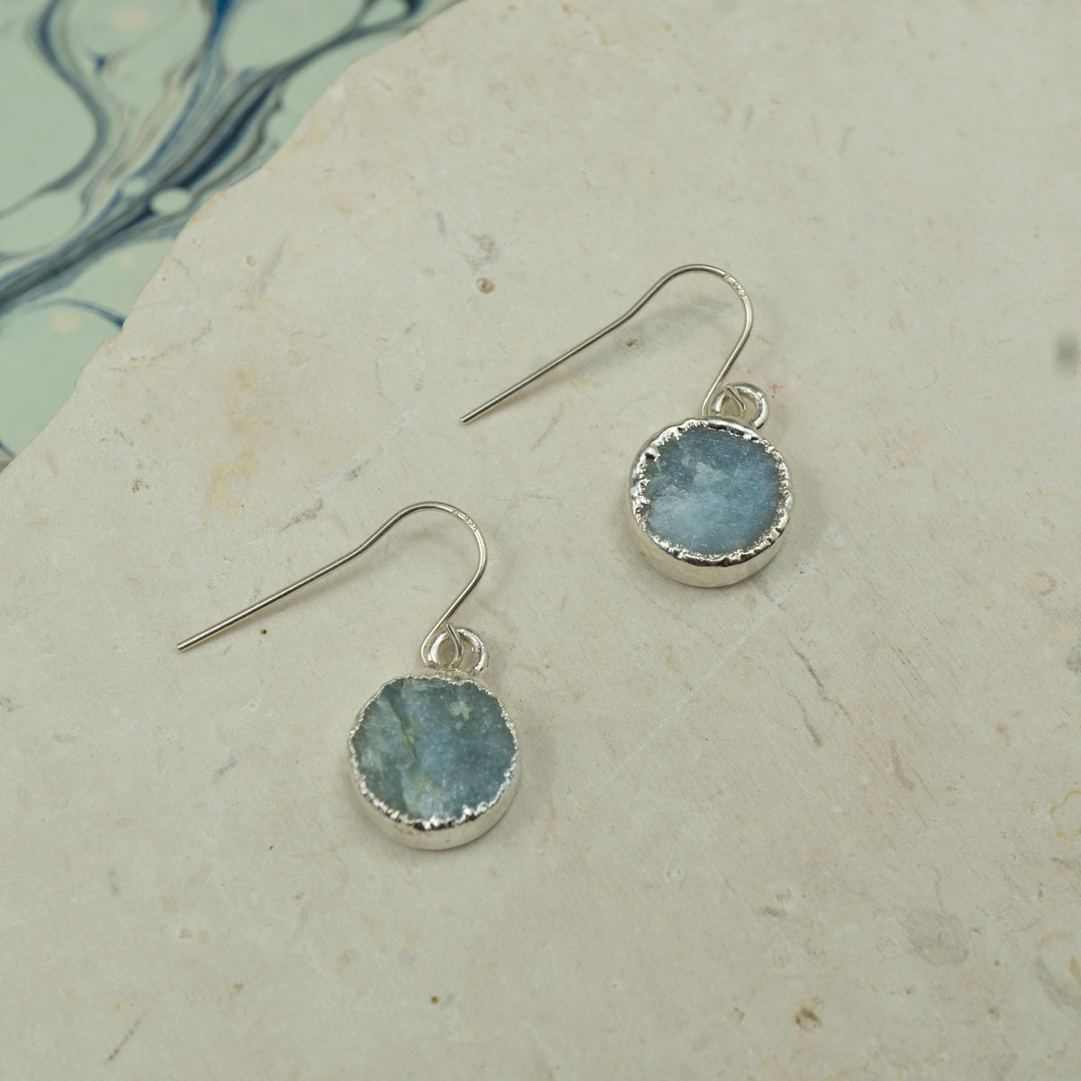 Round raw Blue aquamarine earrings on hooks finished in silver.