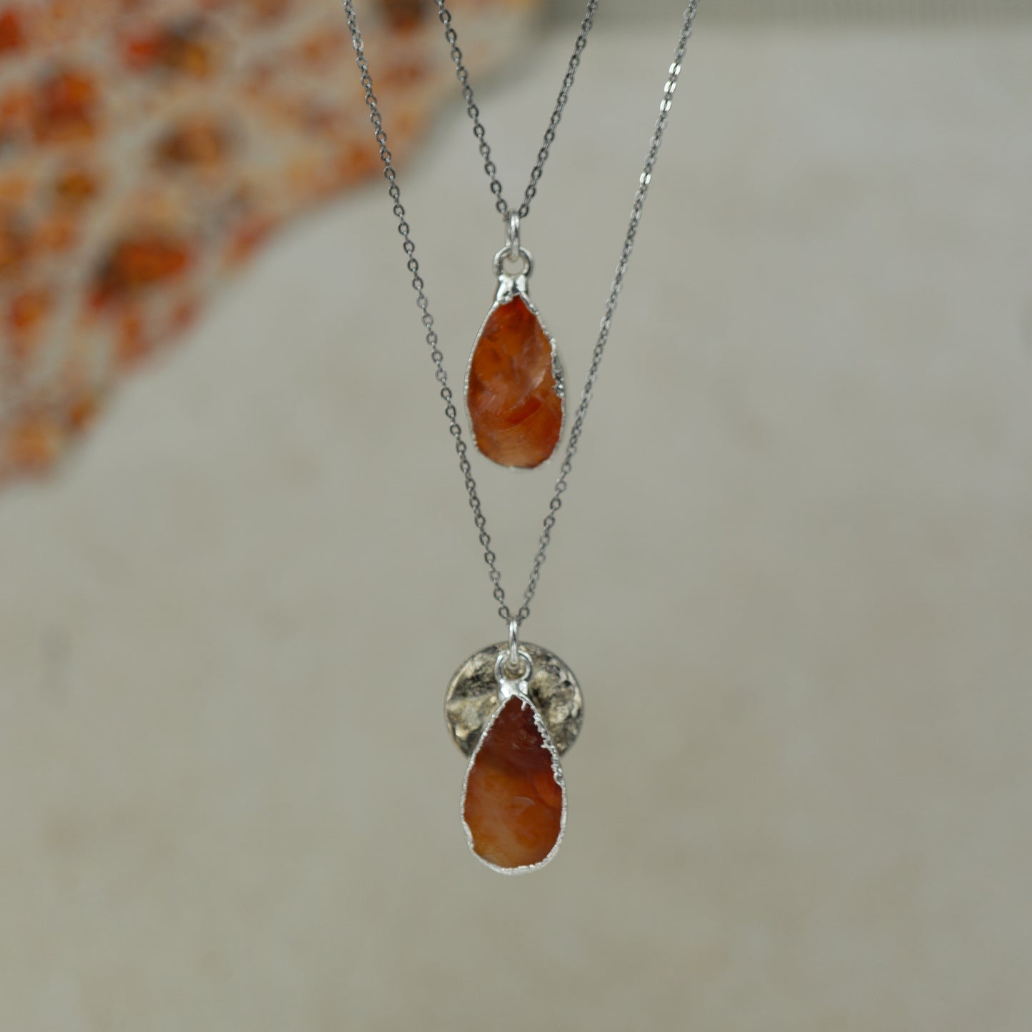 raw orange carnelian teardrop pear shaped pendants finished in silver on a chains.