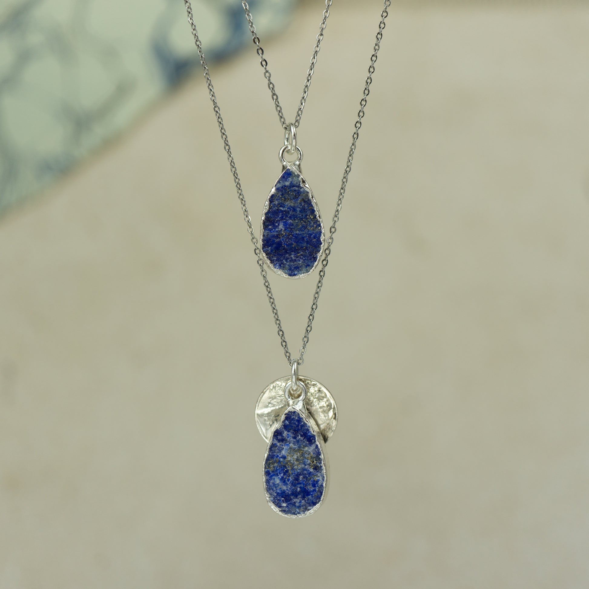 Raw blue Lapis Lazuli teardrop pear shaped pendants finished in silver on a chains.