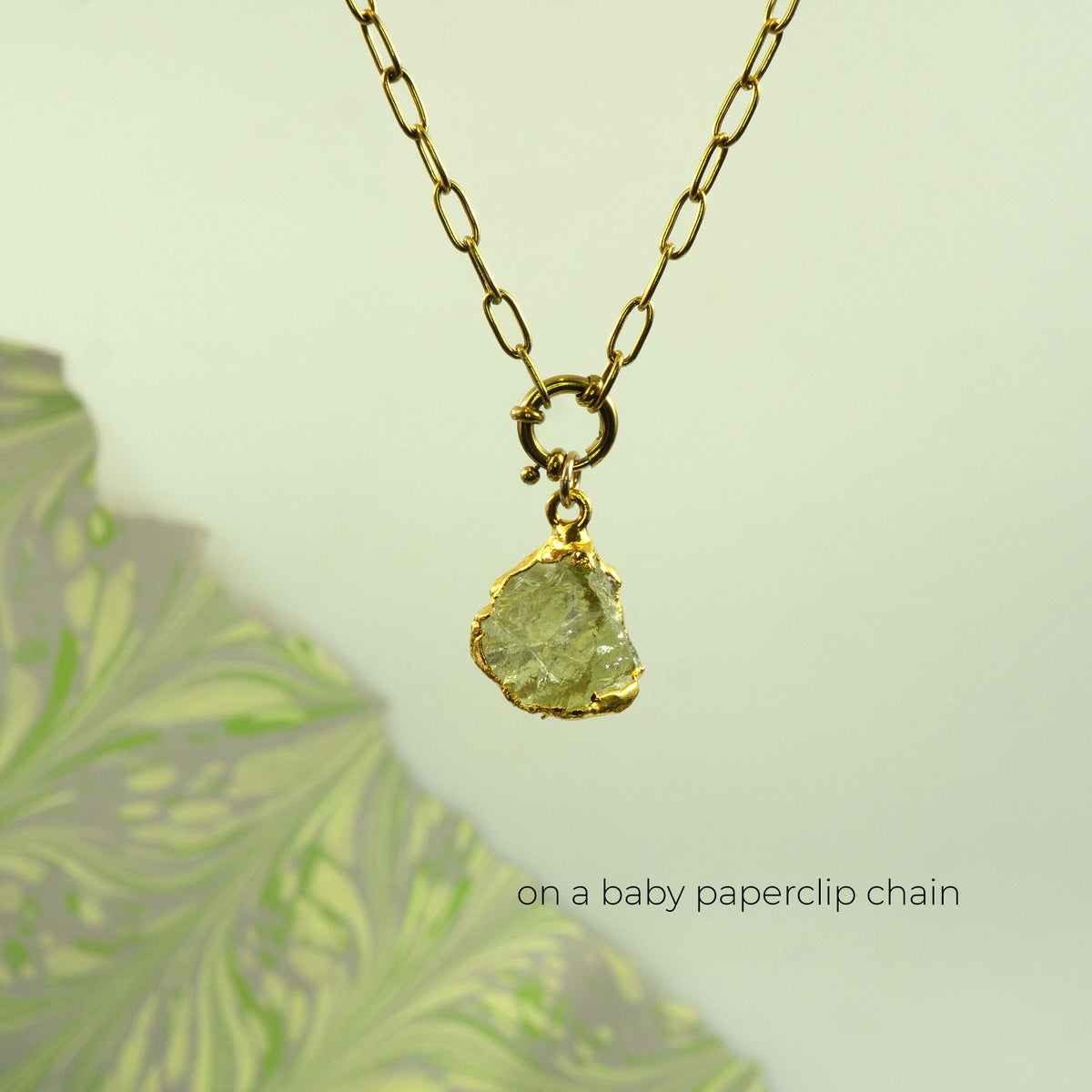 A gold paperclip chain necklace with a raw, irregular-cut light Lemon Quartz gemstone pendant
