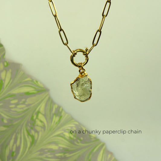 A gold necklace with a chunky paperclip chain and a raw, irregular-cut pale green Lemon Quartz gemstone pendant