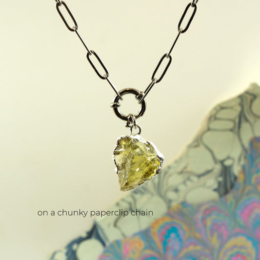 A necklace with a chunky paperclip chain and a raw, irregular faceted yellow-green Lemon Quartz gemstone pendant