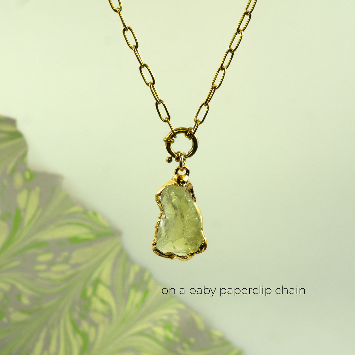 A gold paperclip chain necklace with a raw, irregular-cut Lemon Quartz gemstone pendant