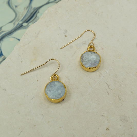 Round raw white moonstone earrings on hooks finished in gold.