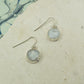 Round raw white moonstone earrings on hooks finished in silver.