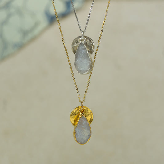 white moonstone teardrop pear shaped pendant with small back disk on a chain in gold and silver.