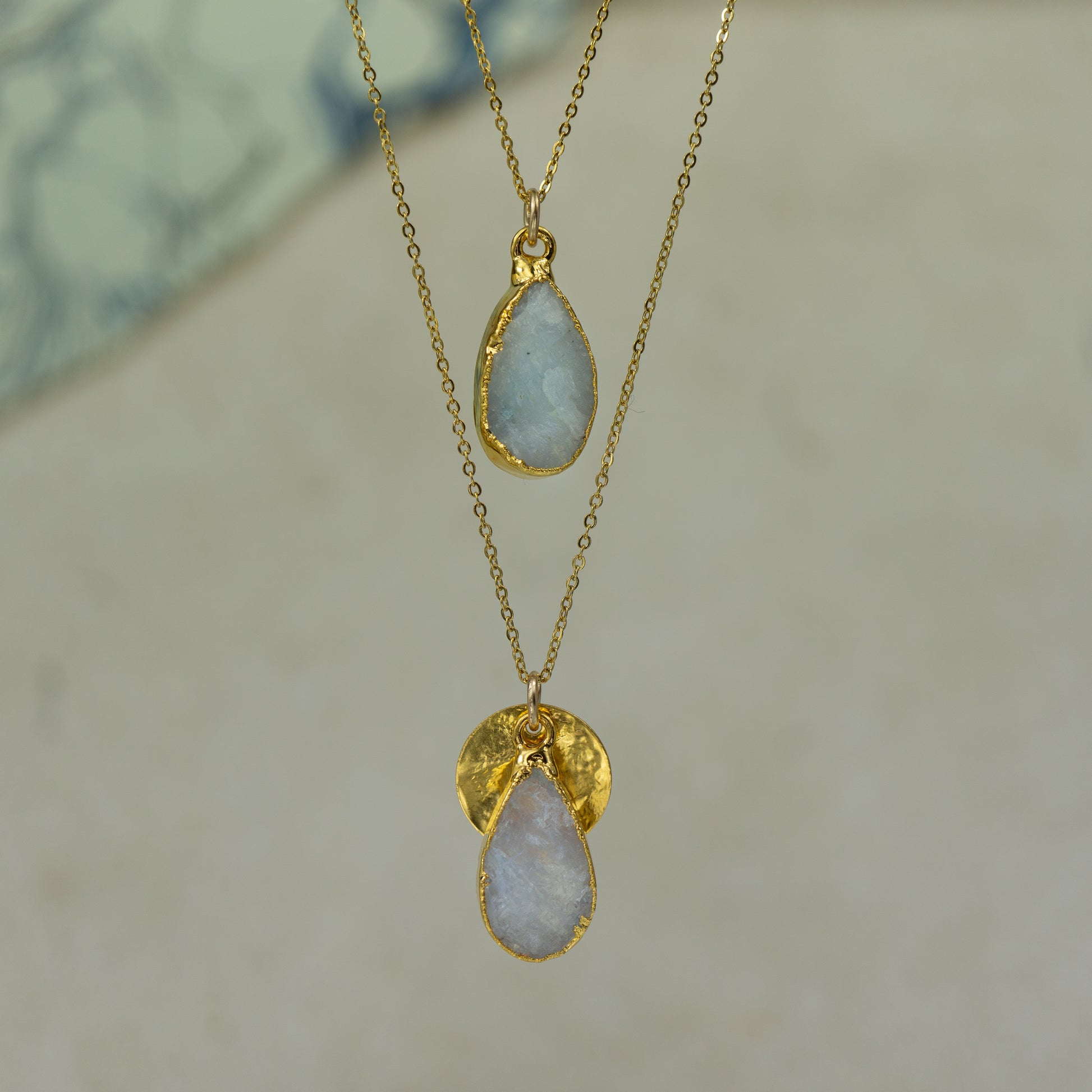 Raw white moonstone teardrop pear shaped pendants finished in gold on a chains.