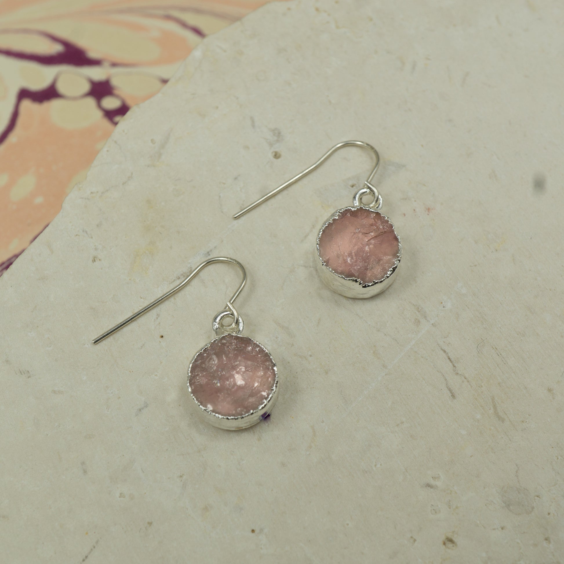 Round raw pink rose quartz earrings on hooks finished in silver.