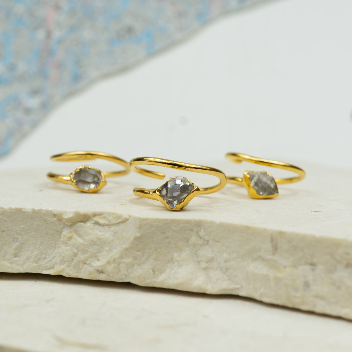 A set of three gold-colored corkscrew-style rings with small clear stones