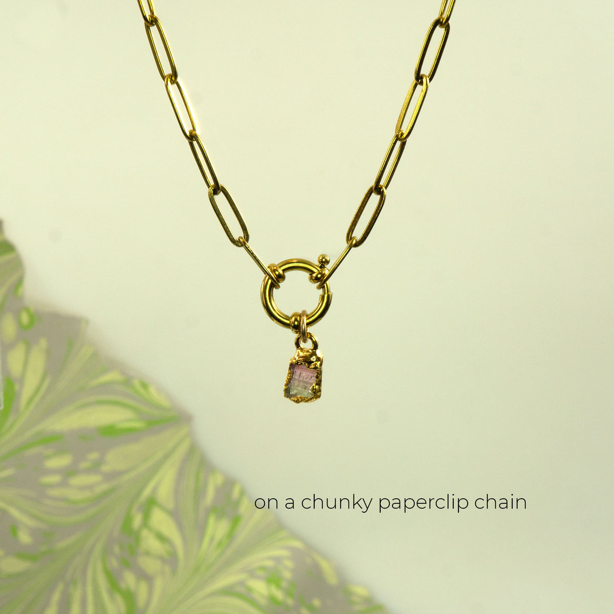A gold paperclip chain necklace with a small dangling pink and green Watermelon Tourmaline gemstone