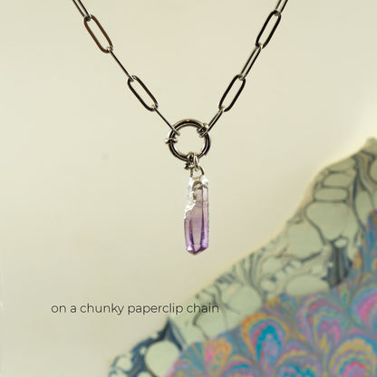 A silver chunky chain necklace with a raw, faceted purple amethyst crystal pendant.