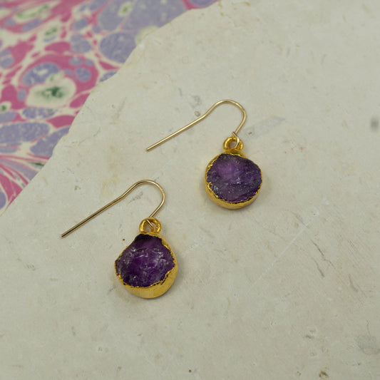 Round purple amethyst earrings on hooks finished in gold.