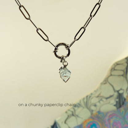 A silver paperclip chain necklace with a ring clasp and a small Aquamarine faceted pendant