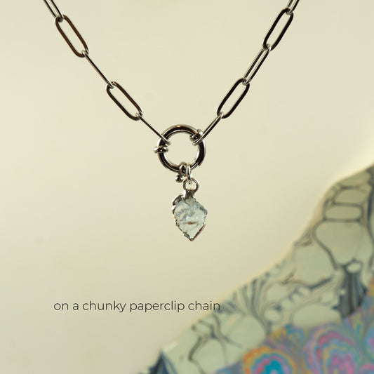 A silver paperclip chain necklace with a ring clasp and a small Aquamarine faceted pendant
