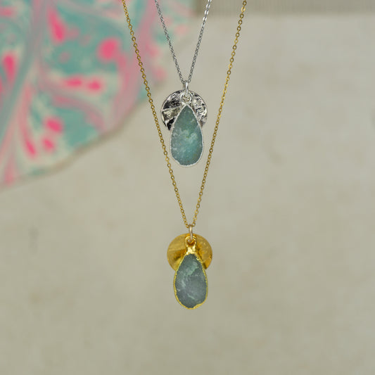 raw blue Aquamarine teardrop pear shaped pendant with small back disk on a chain in gold and silver.