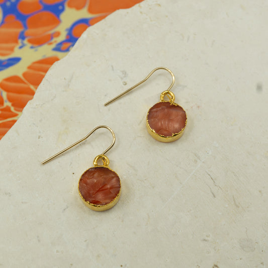 Round raw orange carnelian earrings on hooks finished in gold.