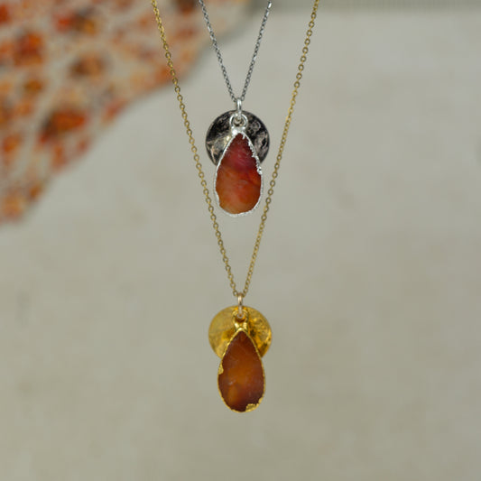 raw orange carnelian teardrop pear shaped pendant with small back disk on a chain in gold and silver.