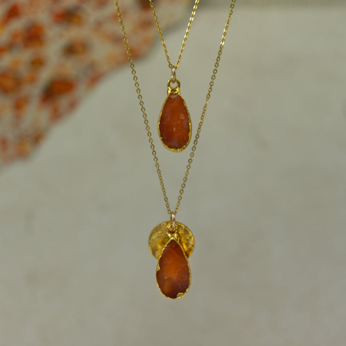 raw orange carnelian teardrop pear shaped pendants finished in gold on a chains.