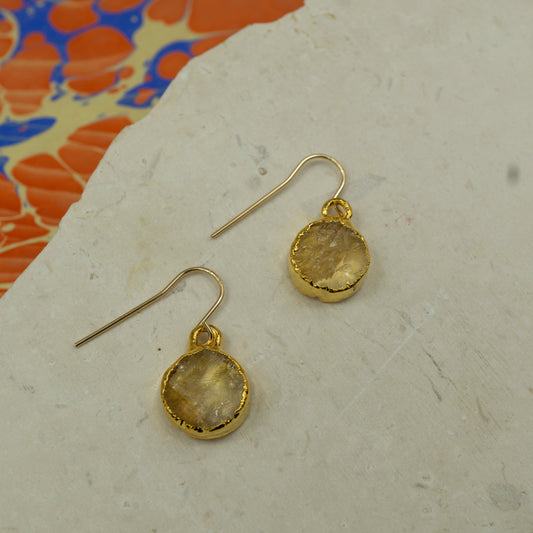 Round raw yellow citrine earrings on hooks finished in gold.