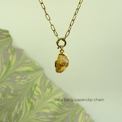 A gold paperclip chain necklace with a raw yellow citrine pendant
