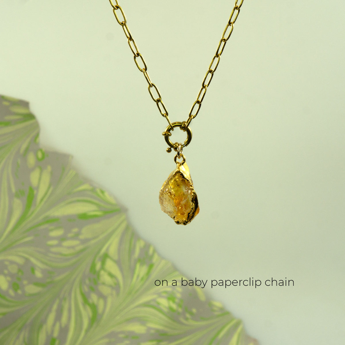 A gold chain necklace with a raw, irregular yellow  citrine gemstone pendant, 