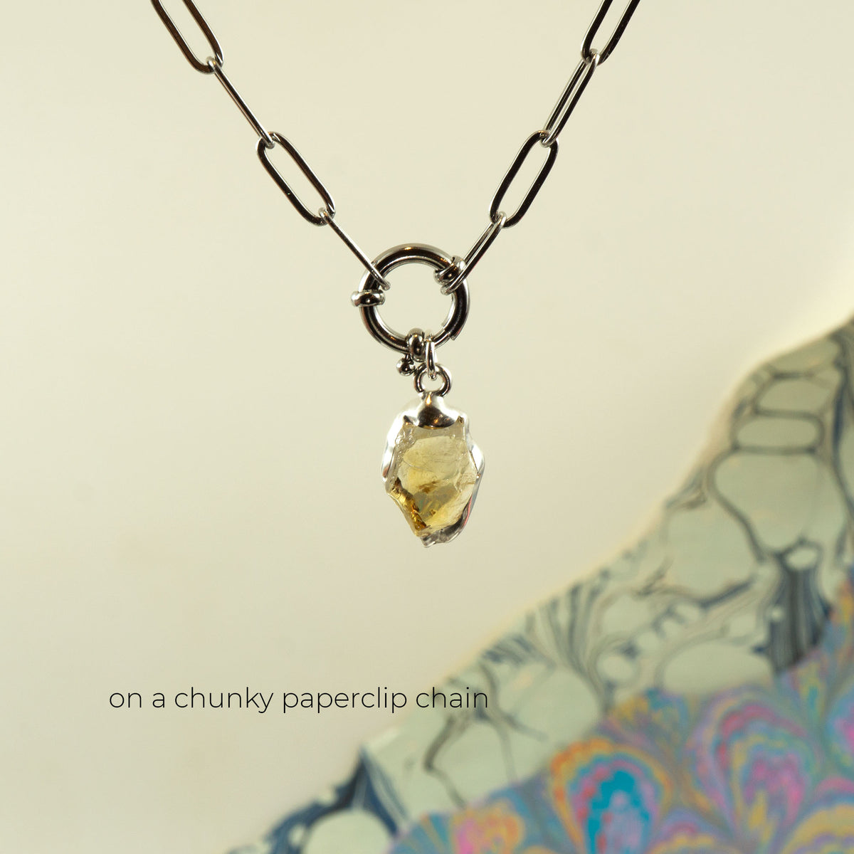 A silver chunky paperclip chain necklace with a polished, irregular-shaped yellow citrine gemstone pendant