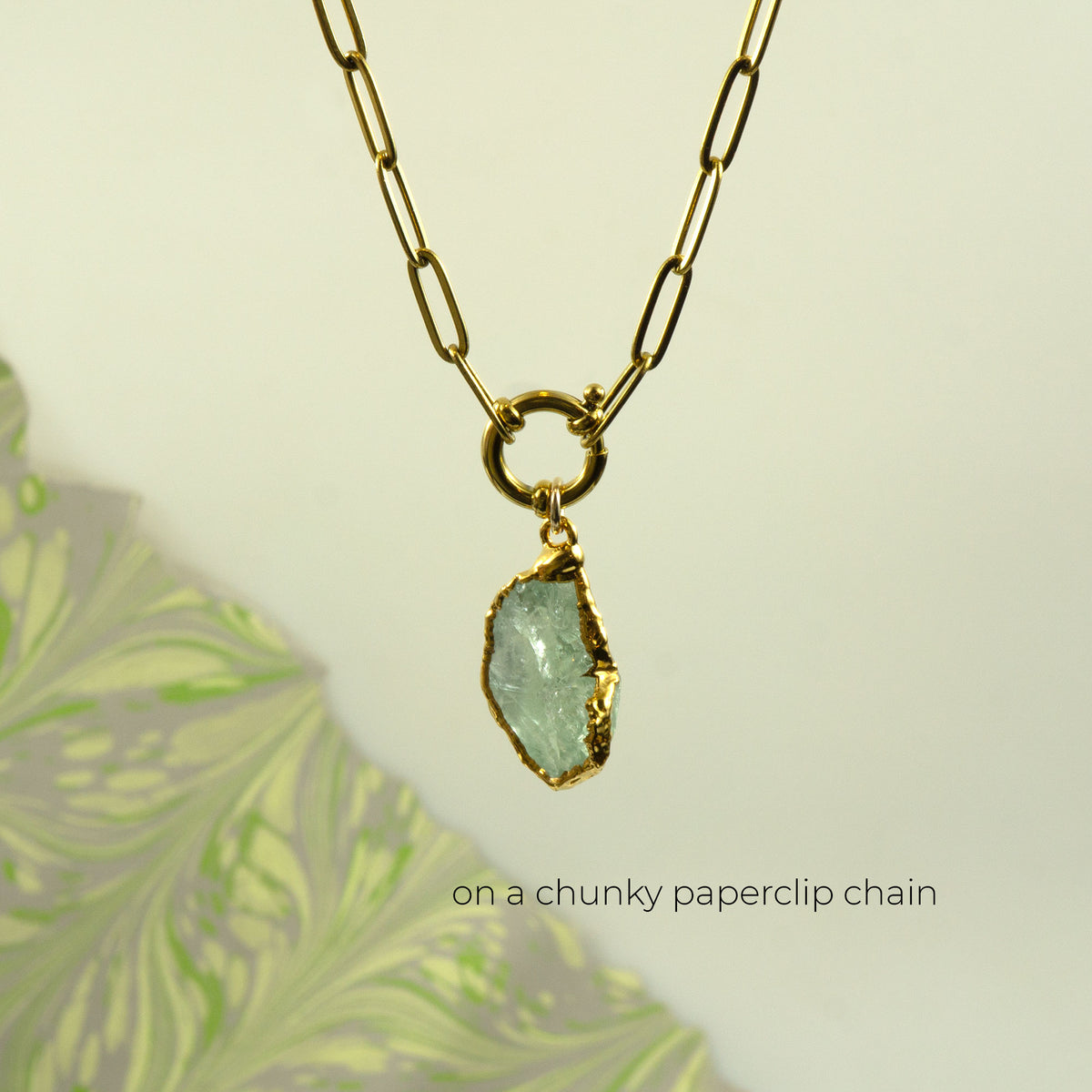 A gold paperclip chain necklace with a raw, irregular light Green Amethyst gemstone pendant