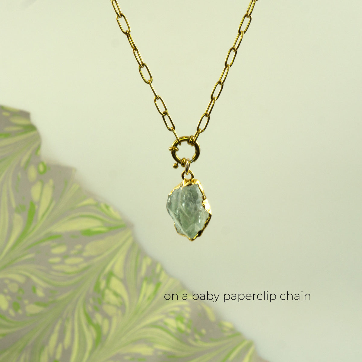 A gold paperclip chain necklace with a raw, irregular-cut Green Amethyst gemstone pendant
