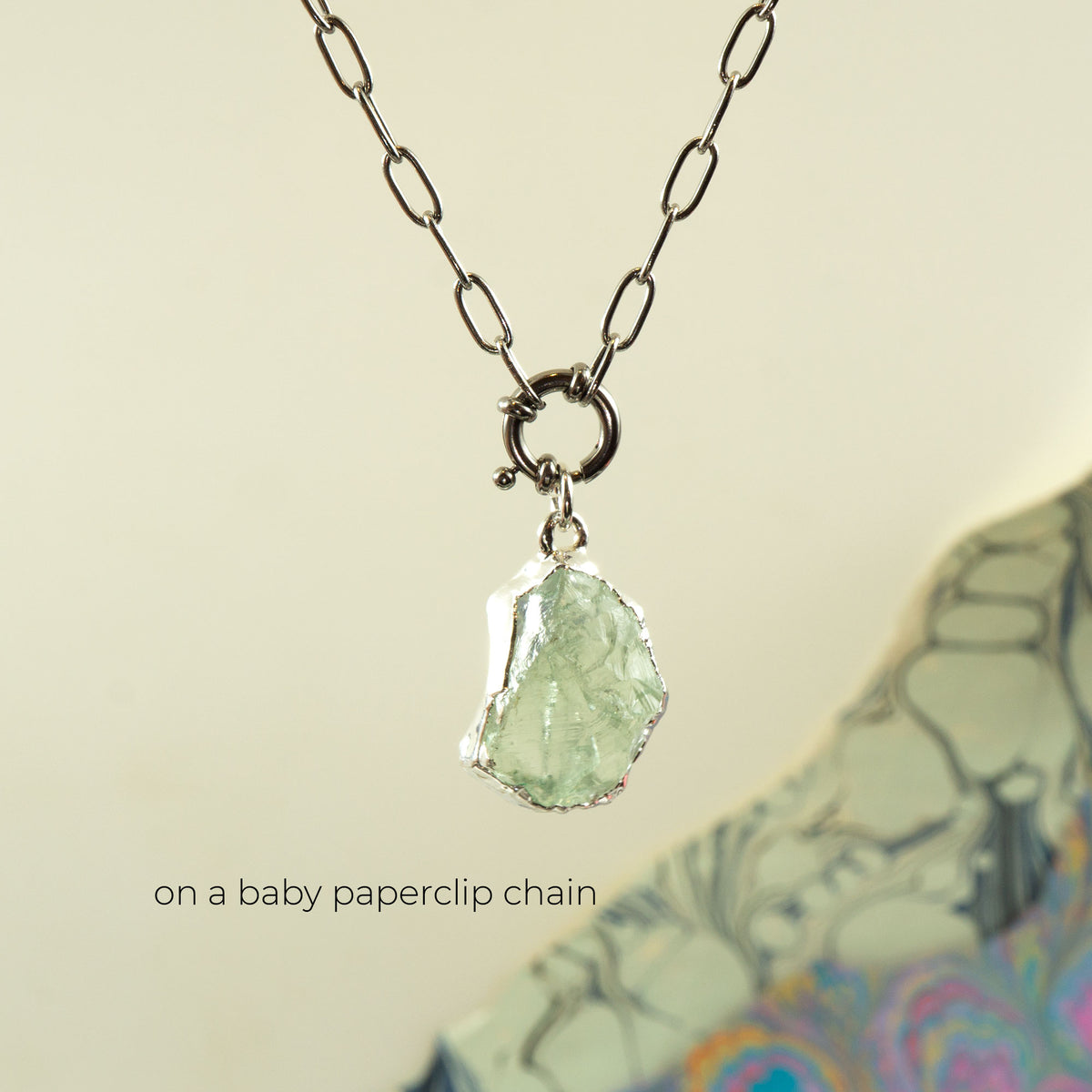 A silver paperclip chain necklace with a raw, irregular Green Amethyst gemstone pendant