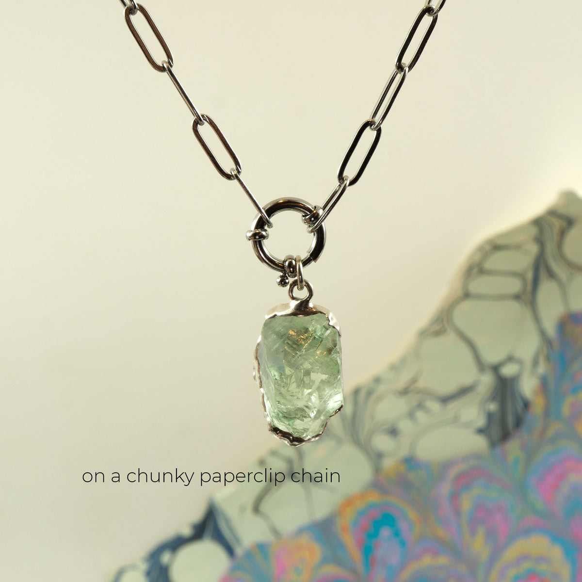 A silver paperclip chain necklace with a raw, rough-cut light Green Amethyst gemstone pendant