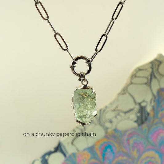 A silver paperclip chain necklace with a raw, rough-cut light Green Amethyst gemstone pendant