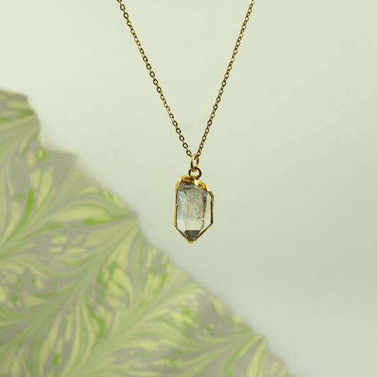 A gold chain necklace with a faceted clear Herkimer Diamond pendant