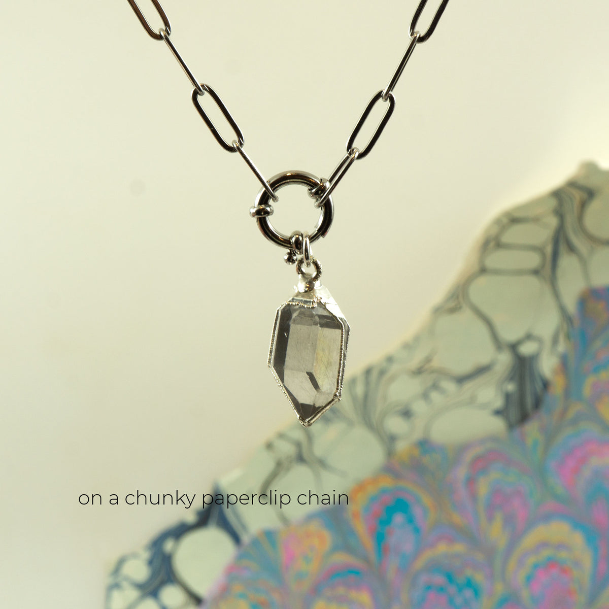A silver paperclip chain necklace with a clear faceted Herkimer diamond gem stone pendant,