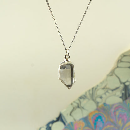 A silver-toned chain necklace with a faceted Herkimer diamond crystal pendant