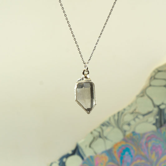 A silver-toned chain necklace with a faceted Herkimer diamond crystal pendant