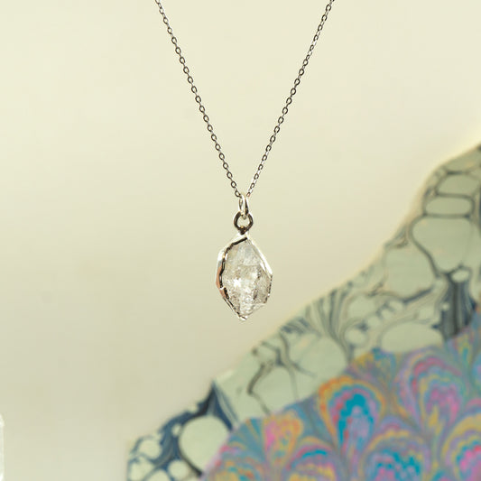 A silver paperclip pendant necklace with a clear faceted Herkimer Diamond gemstone, hanging on a silver chain