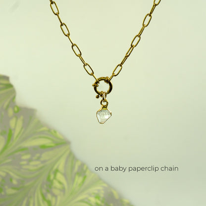 A gold paperclip chain necklace with a small gold clasp and a clear faceted herkimer diamond stone pendant