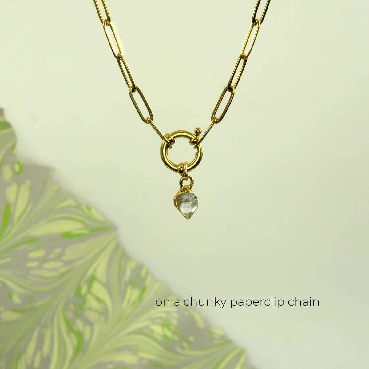 Gold paperclip chain necklace with a small gold ring and a clear faceted heart-shaped crystal herkimer diamond pendant