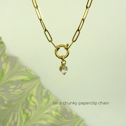 Gold paperclip chain necklace with a small gold ring and a clear faceted heart-shaped crystal herkimer diamond pendant