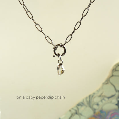 A silver paperclip chain necklace with a small ring clasp and a dangling clear faceted herkimer diamond charm.