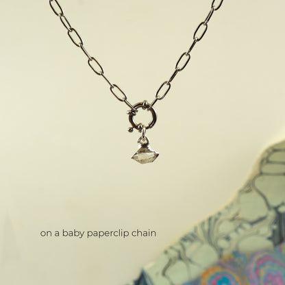 A silver paperclip chain necklace with a small ring clasp and a tiny faceted clear Herkimer Diamond gemstone pendant