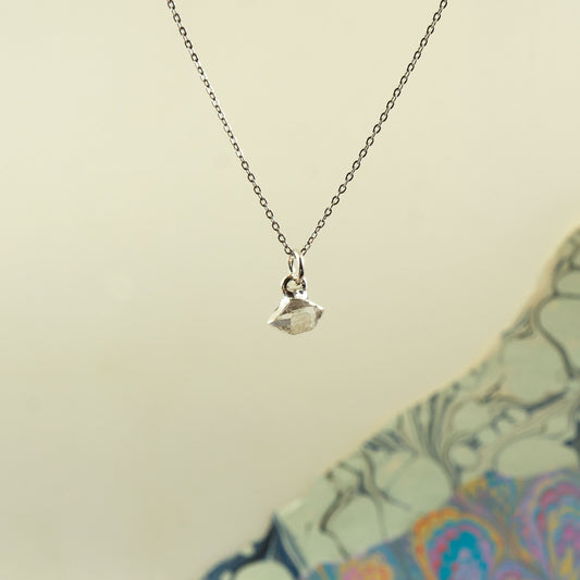 A delicate silver chain necklace with a small faceted Herkimer Diamond pendant.