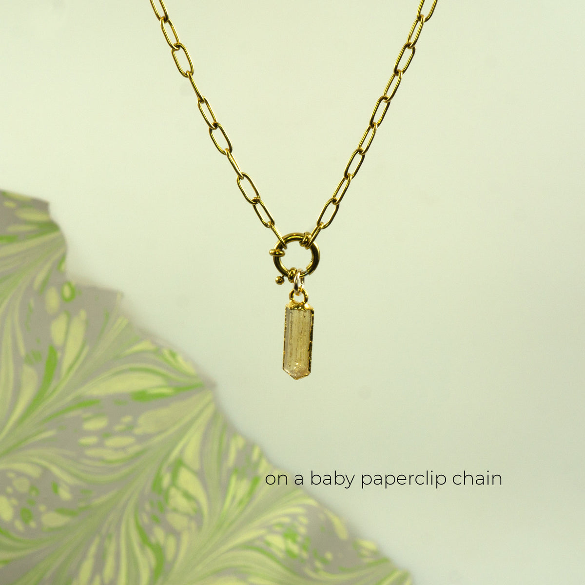A gold paperclip chain necklace with a small rectangular gold Imperial Topaz pendant.