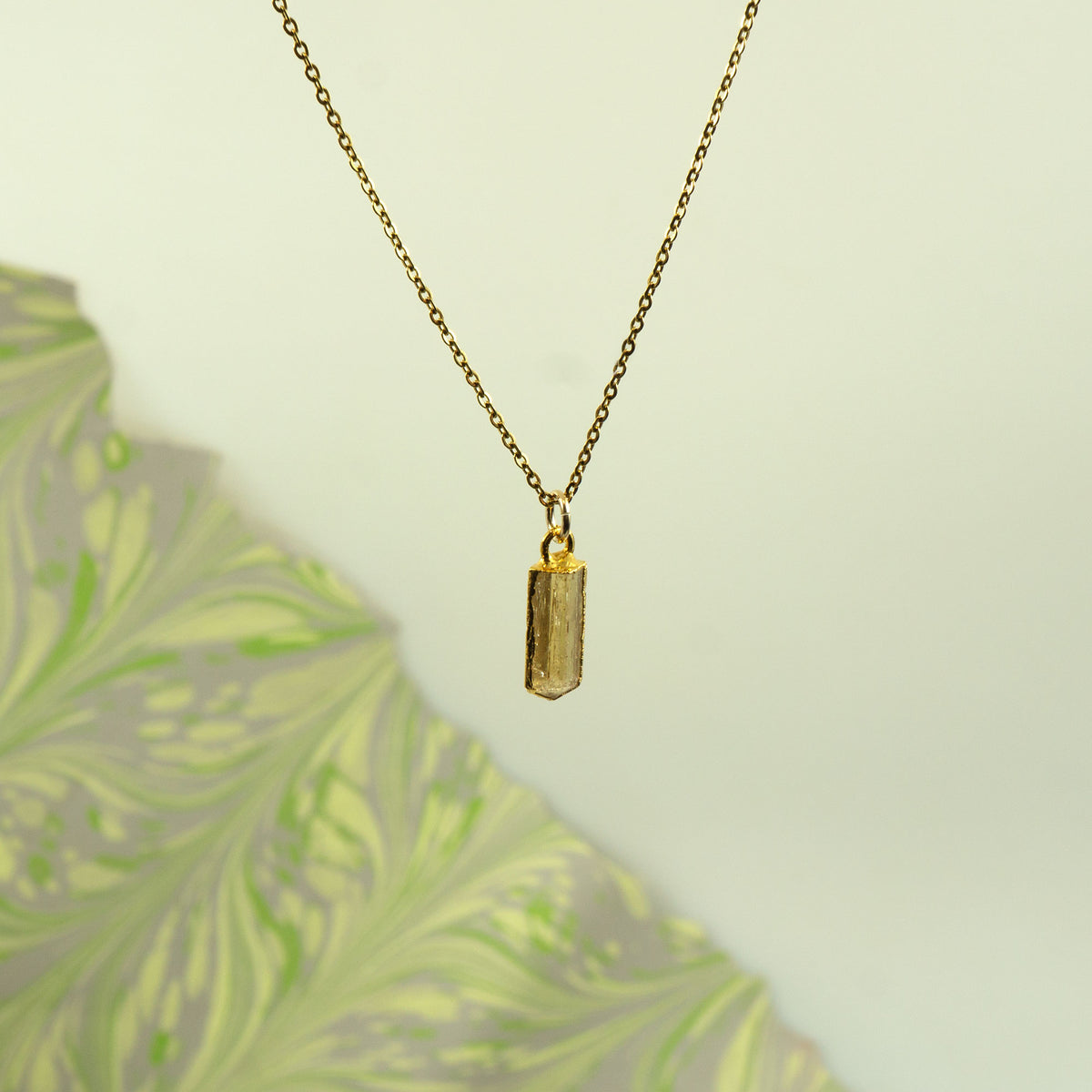 A gold chain necklace with a small rectangular faceted crystal Imperial Topaz pendant