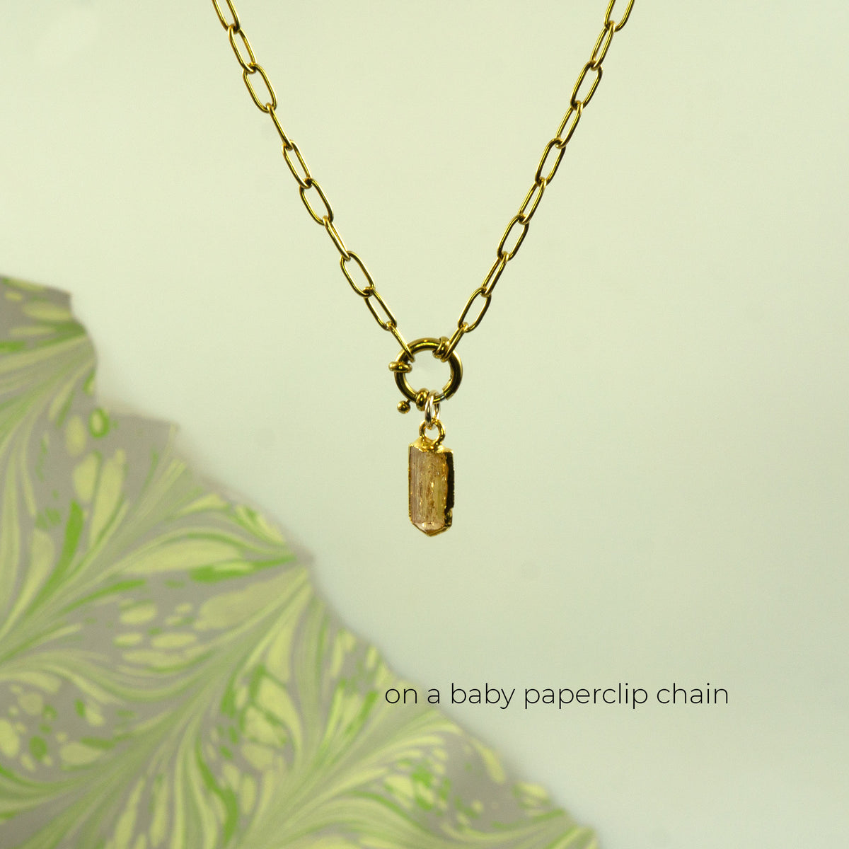 A gold paperclip chain necklace with a small rectangular faceted Imperial Topaz gemstone pendant.