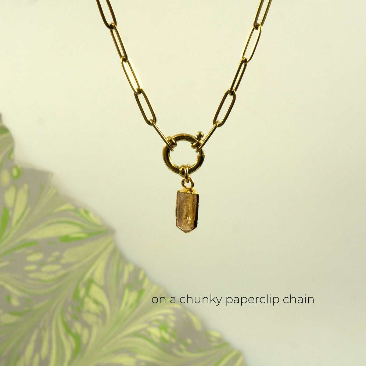 A gold paperclip chain necklace with a small rectangular faceted Imperial Topaz crystal pendant.